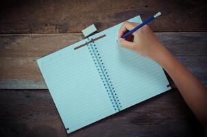 Hand writing in open notebook on table photo