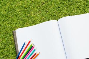 Color pencil and sketchbook on fresh spring green grass photo