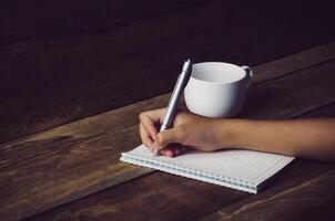 Hand writing in open notebook on table photo