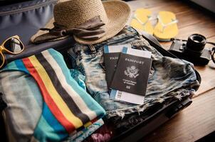 Clothing traveler's Passport, wallet, glasses, smart phone devices, on a wooden floor in the luggage ready to travel. photo