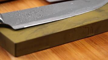 Sharpening knives with a Whetstone. Knife sharpening. Sharp knife and sharpening stone on a wooden cutting board. video