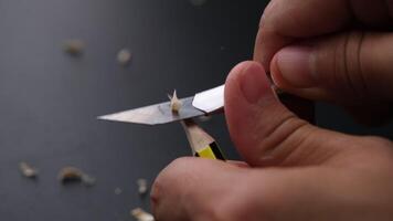 Hands sharpening pencil using utility knife, close up. video