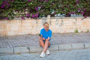 un mujer sentado en un bordillo con su teléfono foto