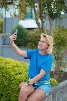 a woman in a blue shirt is taking a selfie photo