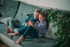 dos niños sentado en un sofá con un teléfono foto