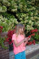 un joven niña en un rosado camisa es utilizando su teléfono foto