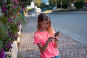 un joven niña en un rosado camisa es utilizando su teléfono foto