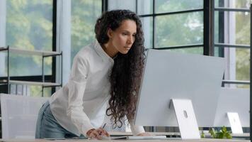 Busy successful businesswoman working in office writing data from computer beautiful female professional creative manager develops plan for development of new project writes tasks using application photo