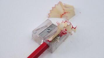 Colored pencils or pencils and sharpener isolated on white background. Red wooden pencil and pencil shavings on white table. video