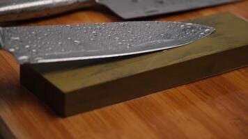 Sharpening knives with a Whetstone. Knife sharpening. Sharp knife and sharpening stone on a wooden cutting board. video