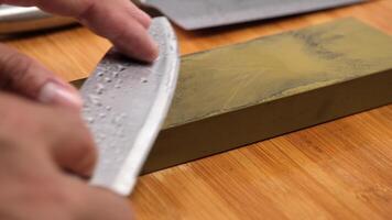 Sharpening knives with a Whetstone. Knife sharpening. Sharp knife and sharpening stone on a wooden cutting board. video