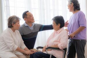 Asian young nurse support couple senior older woman in a wheelchair. elderly mature and a group of senior friends living in the hospital. socializing of retired people. photo