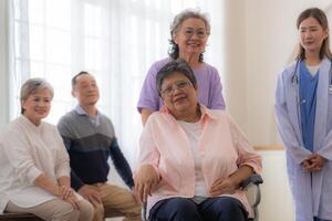 Asian young nurse support couple senior older woman in a wheelchair. elderly mature and a group of senior friends living in the hospital. socializing of retired people. photo