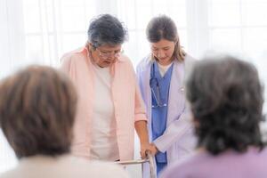 Asian young nurse support couple senior older woman in a wheelchair. elderly mature and a group of senior friends living in the hospital. socializing of retired people. photo