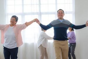 asiático más viejo masculino y hembras personas danza con su socios en un bailando piso en vivo espacio. contento más viejo Pareja ejecutando obtener ejercicio. alegre despreocupado retirado mayor amigos disfrutando relajación foto