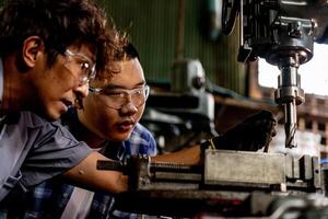 asiático trabajador en producción planta perforación a máquina. profesional trabajador cerca perforación máquina en fábrica. refinamiento metal trabajando interno acero superficie en torno amoladora máquina con volador chispas. foto