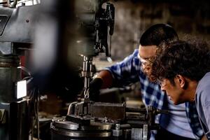 Asian worker in production plant drilling at machine. Professional worker near drilling machine on factory. finishing metal working internal steel surface on lathe grinder machine with flying sparks. photo