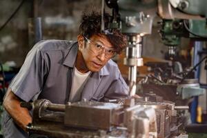 Engineer worker in production plant drilling at machine. Professional worker near drilling machine on factory. man inspecting and repairing machine for operation in workshop. photo