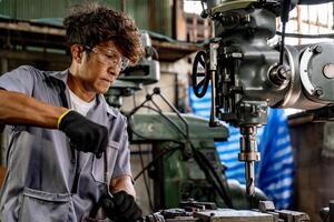 Engineer worker in production plant drilling at machine. Professional worker near drilling machine on factory. man inspecting and repairing machine for operation in workshop. photo