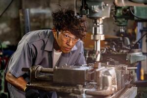 Engineer worker in production plant drilling at machine. Professional worker near drilling machine on factory. man inspecting and repairing machine for operation in workshop. photo