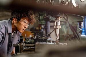 Engineer worker in production plant drilling at machine. Professional worker near drilling machine on factory. man inspecting and repairing machine for operation in workshop. photo