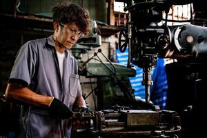 Engineer worker in production plant drilling at machine. Professional worker near drilling machine on factory. man inspecting and repairing machine for operation in workshop. photo