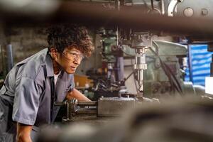 Engineer worker in production plant drilling at machine. Professional worker near drilling machine on factory. man inspecting and repairing machine for operation in workshop. photo