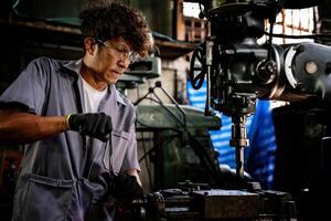 Engineer worker in production plant drilling at machine. Professional worker near drilling machine on factory. man inspecting and repairing machine for operation in workshop. photo