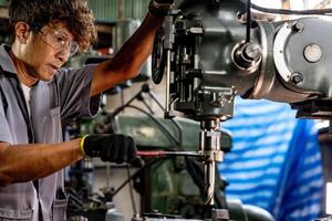 Engineer worker in production plant drilling at machine. Professional worker near drilling machine on factory. man inspecting and repairing machine for operation in workshop. photo
