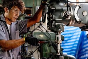 Engineer worker in production plant drilling at machine. Professional worker near drilling machine on factory. man inspecting and repairing machine for operation in workshop. photo