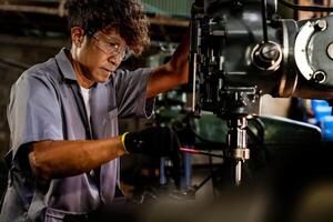 Engineer worker in production plant drilling at machine. Professional worker near drilling machine on factory. man inspecting and repairing machine for operation in workshop. photo