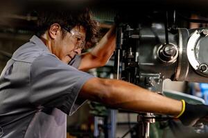 Engineer worker in production plant drilling at machine. Professional worker near drilling machine on factory. man inspecting and repairing machine for operation in workshop. photo