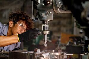 Engineer worker in production plant drilling at machine. Professional worker near drilling machine on factory. man inspecting and repairing machine for operation in workshop. photo