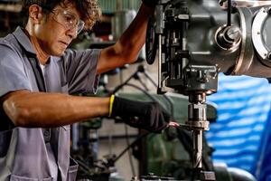 Engineer worker in production plant drilling at machine. Professional worker near drilling machine on factory. man inspecting and repairing machine for operation in workshop. photo