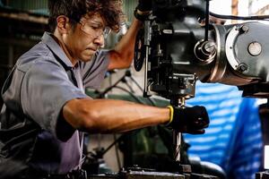 Engineer worker in production plant drilling at machine. Professional worker near drilling machine on factory. man inspecting and repairing machine for operation in workshop. photo