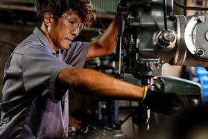 Engineer worker in production plant drilling at machine. Professional worker near drilling machine on factory. man inspecting and repairing machine for operation in workshop. photo