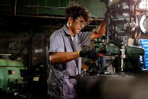 Engineer worker in production plant drilling at machine. Professional worker near drilling machine on factory. man inspecting and repairing machine for operation in workshop. photo