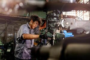 Engineer worker in production plant drilling at machine. Professional worker near drilling machine on factory. man inspecting and repairing machine for operation in workshop. photo