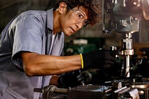 Engineer worker in production plant drilling at machine. Professional worker near drilling machine on factory. man inspecting and repairing machine for operation in workshop. photo