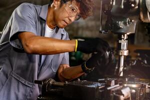 Engineer worker in production plant drilling at machine. Professional worker near drilling machine on factory. man inspecting and repairing machine for operation in workshop. photo