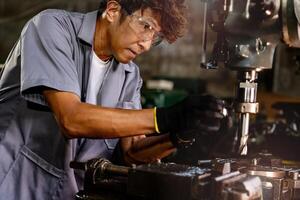 ingeniero trabajador en producción planta perforación a máquina. profesional trabajador cerca perforación máquina en fábrica. hombre inspeccionando y reparando máquina para operación en taller. foto