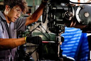 Engineer worker in production plant drilling at machine. Professional worker near drilling machine on factory. man inspecting and repairing machine for operation in workshop. photo