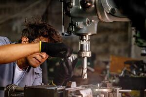 Engineer worker in production plant drilling at machine. Professional worker near drilling machine on factory. man inspecting and repairing machine for operation in workshop. photo