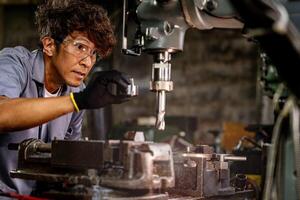 Engineer worker in production plant drilling at machine. Professional worker near drilling machine on factory. man inspecting and repairing machine for operation in workshop. photo