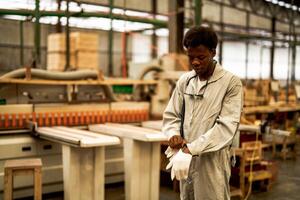 African man workers engineering standing with confidence with working suite dress and hand glove in front machine. Concept of smart industry worker operating. Wood factory produce wood palate. photo