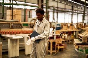 African man workers engineering standing with confidence with working suite dress and hand glove in front machine. Concept of smart industry worker operating. Wood factory produce wood palate. photo