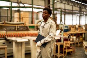 African man workers engineering standing with confidence with working suite dress and hand glove in front machine. Concept of smart industry worker operating. Wood factory produce wood palate. photo