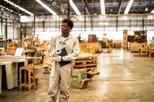 African man workers engineering standing with confidence with working suite dress and hand glove in front machine. Concept of smart industry worker operating. Wood factory produce wood palate. photo