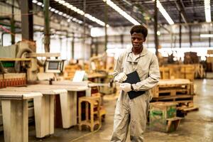 African man workers engineering standing with confidence with working suite dress and hand glove in front machine. Concept of smart industry worker operating. Wood factory produce wood palate. photo