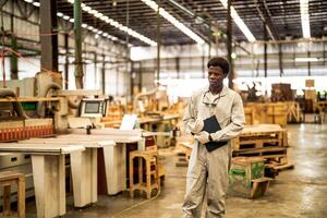 African man workers engineering standing with confidence with working suite dress and hand glove in front machine. Concept of smart industry worker operating. Wood factory produce wood palate. photo